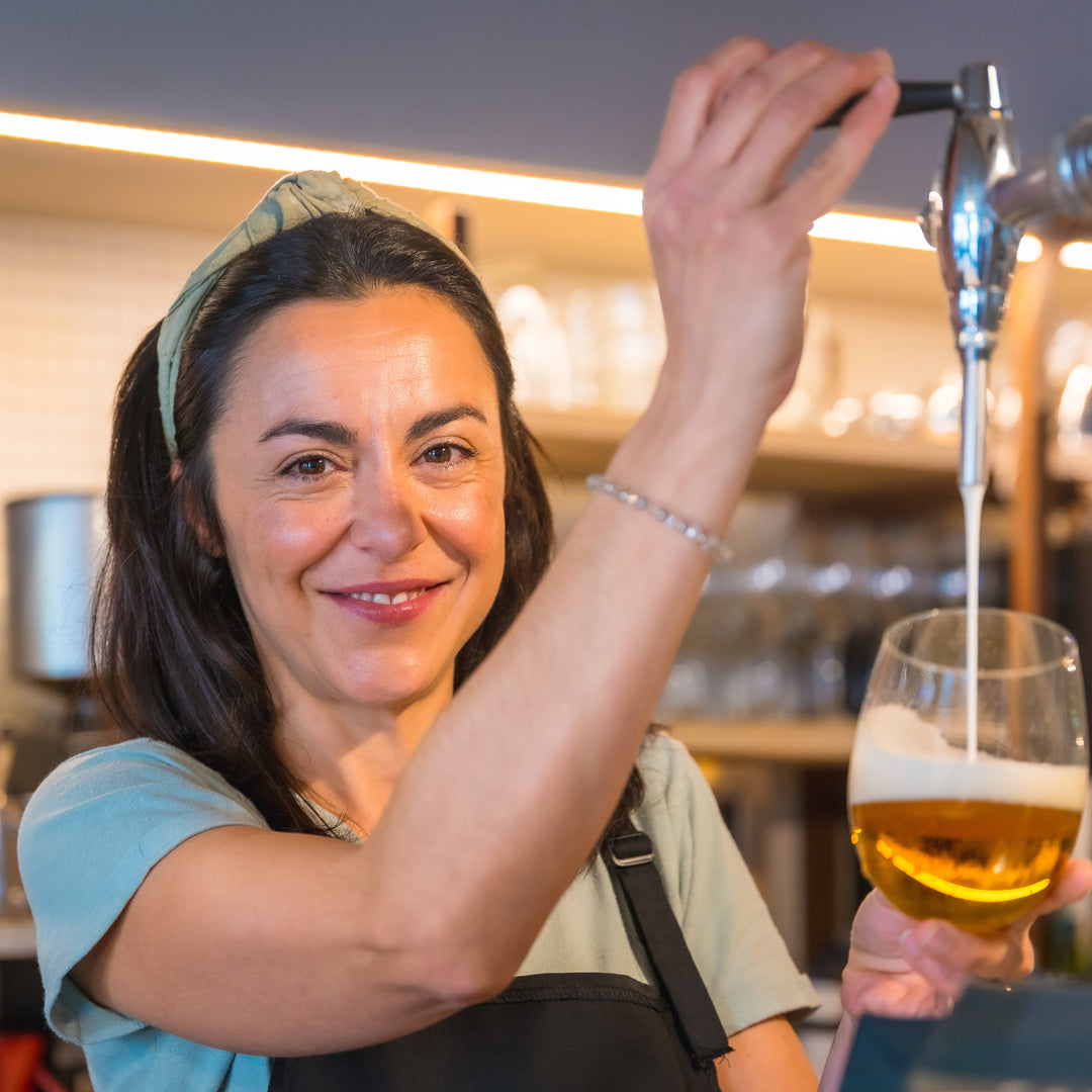 Woman pouring beer from a tap into a glass in a bar setting
